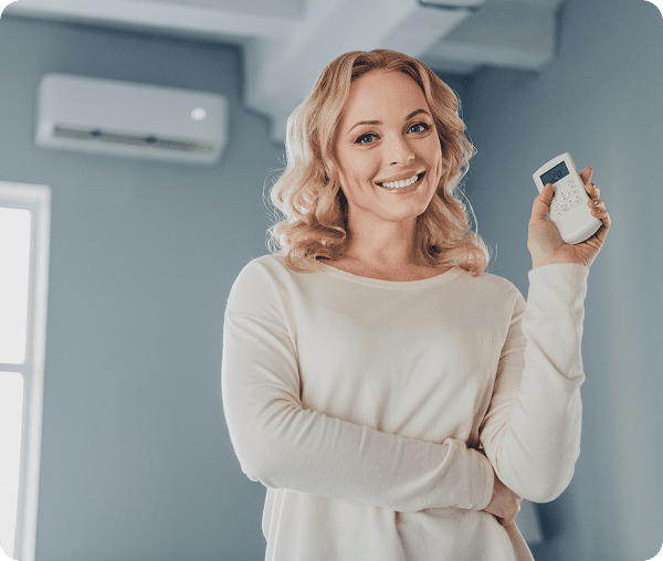 Woman smiling with air conditioner remote control.