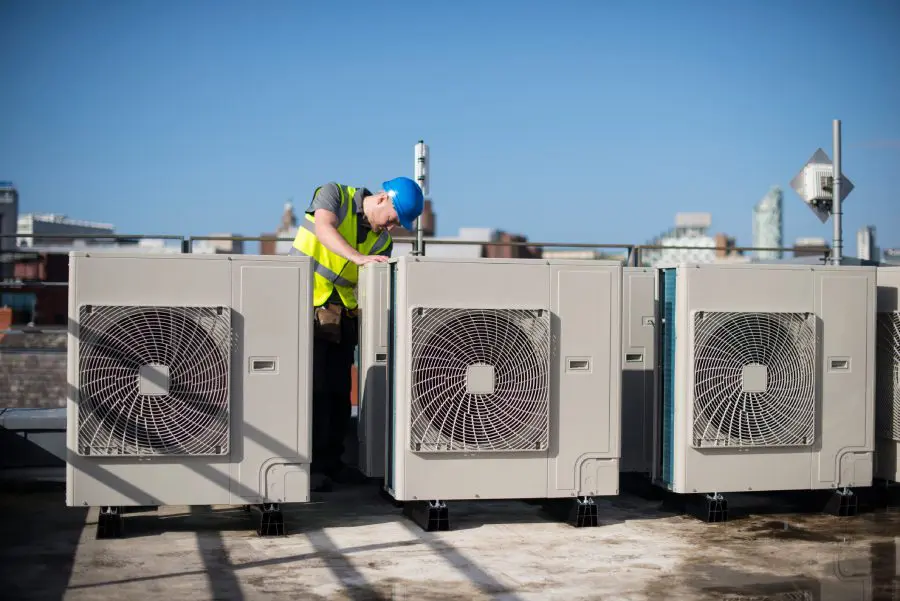 Technician inspecting rooftop air conditioning units.